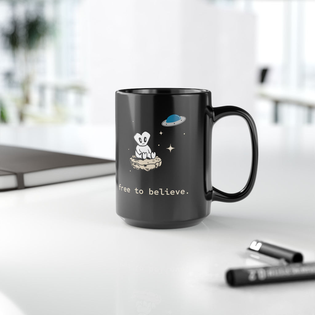 Alien Sitting on Rock Black Mug — “free to believe.” 11oz & 15oz